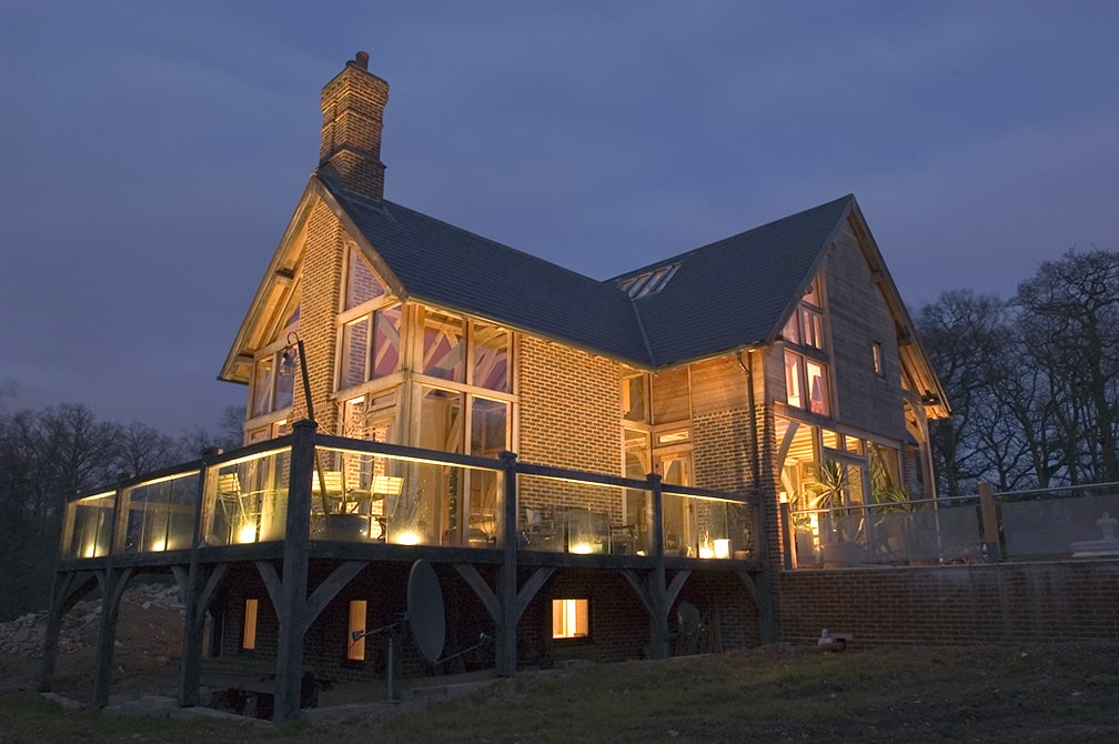 External view of Lower Ratlake oak framed house at dusk with outside lights on