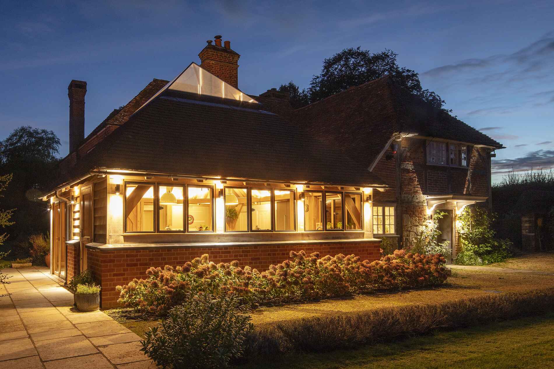 External view of church farmhouse with oak framing at dusk, with internal lights on