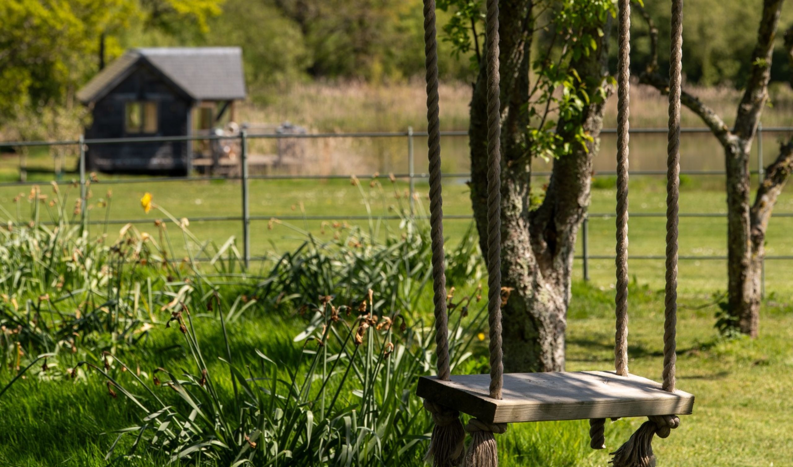Oak frame boathouse in the distance with a wooden swing